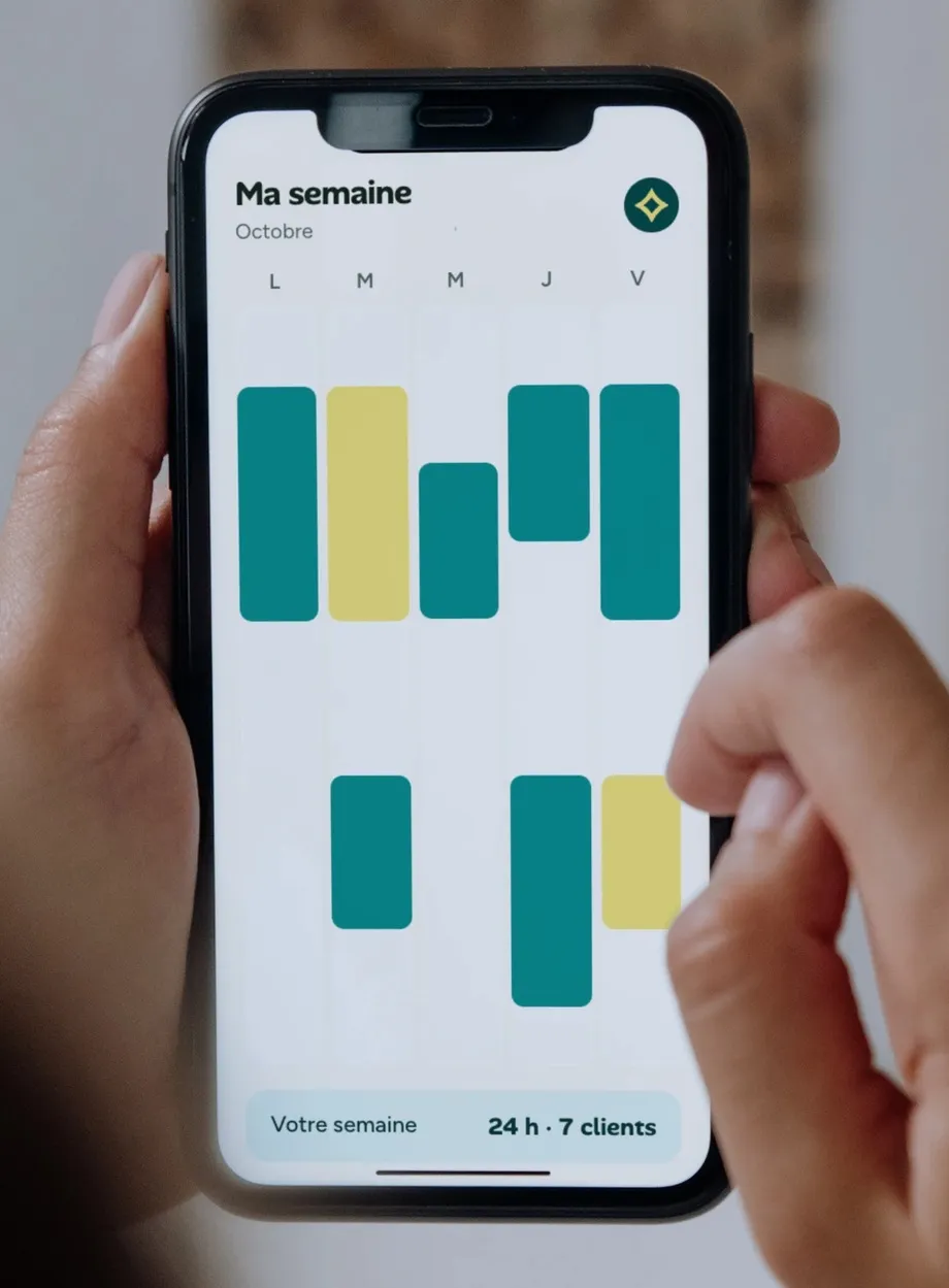 Un téléphone tenu en main, ouvert sur un planning de la semaine.
